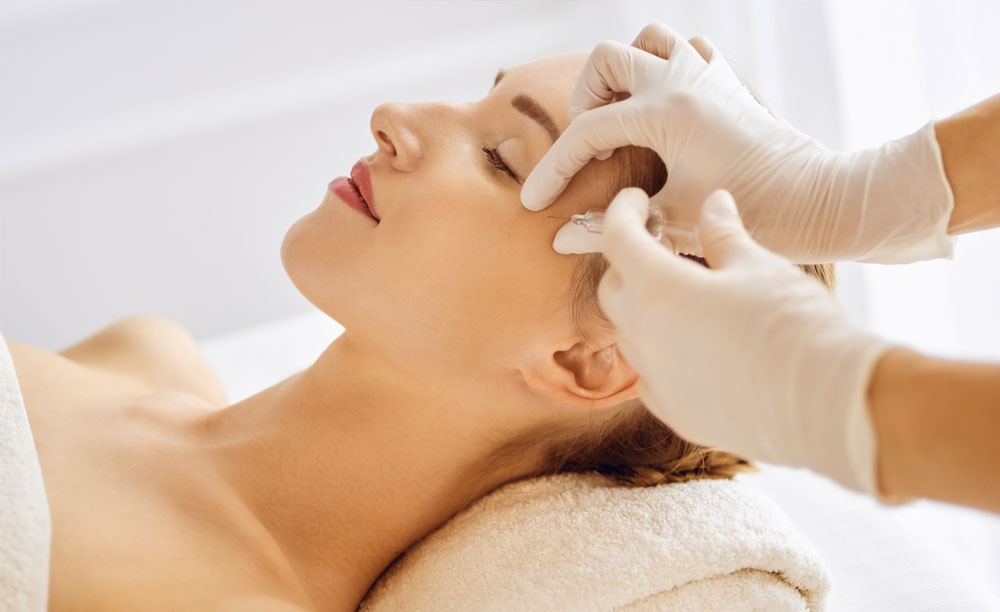 Beautiful woman receiving beauty injections with closed eyes. Beautician doctor hands doing beauty procedure to female face with syringe. Cosmetic medicine and surgery concept